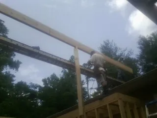 Carpenter setting a ridge beam over a new addition frame — Ice Dam Removal by Roofing Brothers in New Weston