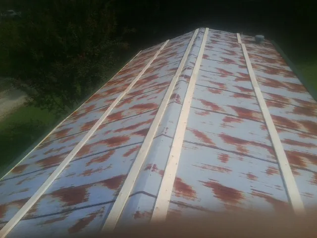 Rusted metal roof panels with new wood purlins before replacement — Storm Damage Roof Repair in New Weston by Roofing Brothers