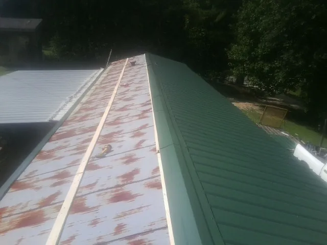 Old rusted panels beside newly installed green metal roofing — Wind Damage Roof Repair by Roofing Brothers in New Weston