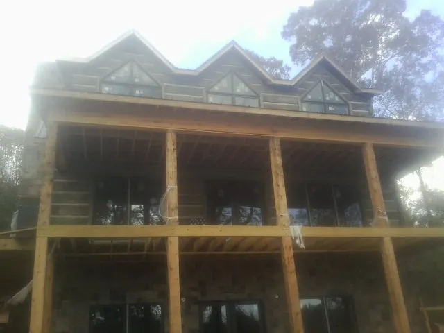 Dormers and porch framing on a large log home under construction — Roof Coating work by our crew in New Weston