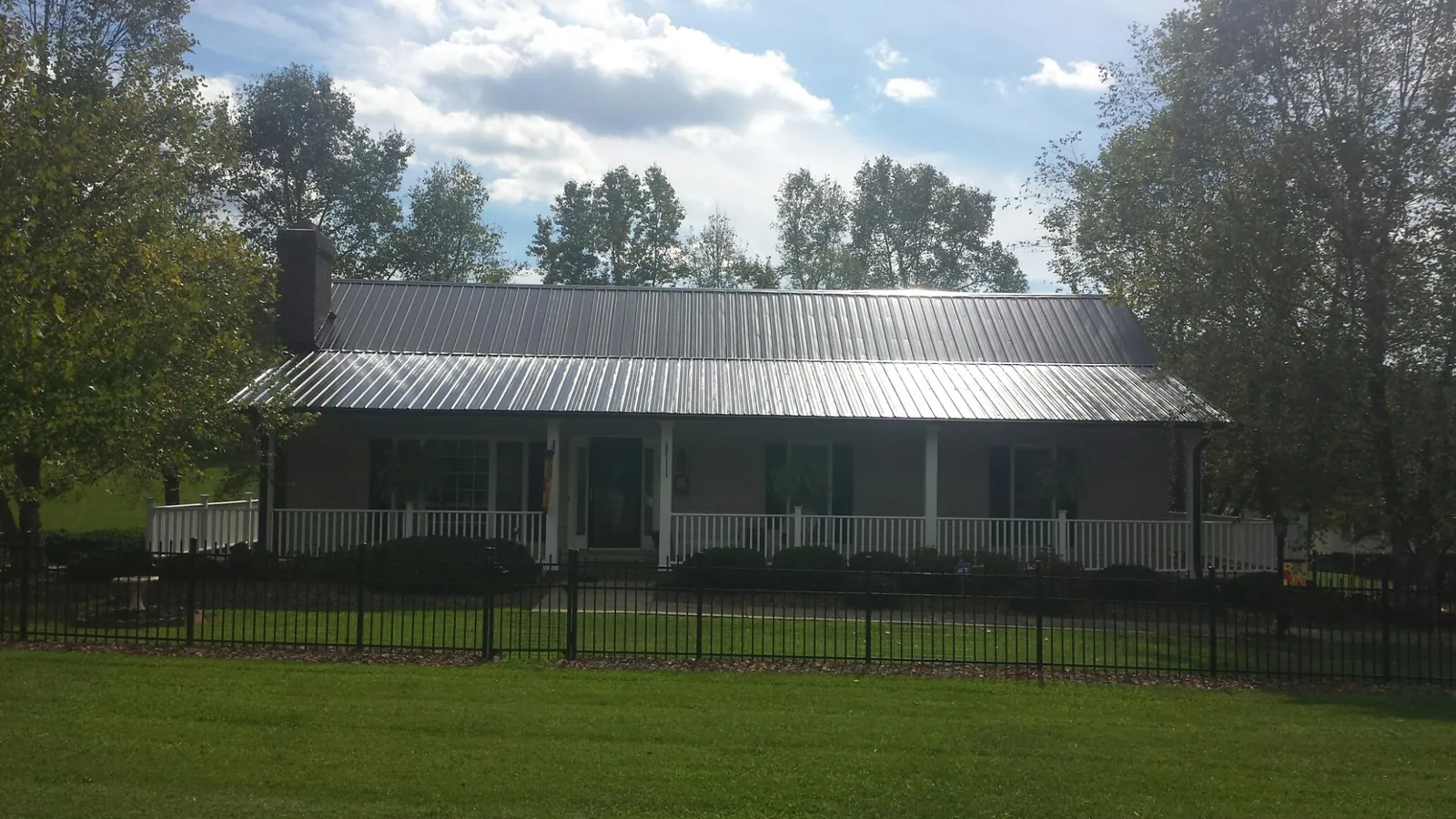 Gray metal roof on a brick ranch with a full width front porch — Gutter Guard Installation work by our crew in New Weston