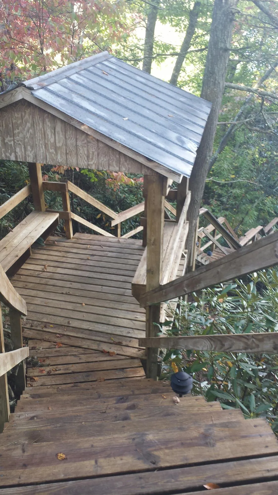 Metal roofed shelter over wooden steps on a wooded walkway — Skylight Repair & Installation work by our crew in New Weston